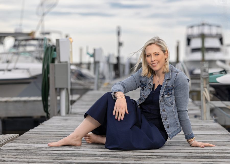Brittany Peckham sitting on a dock at a Connecticut marina, wearing a denim jacket